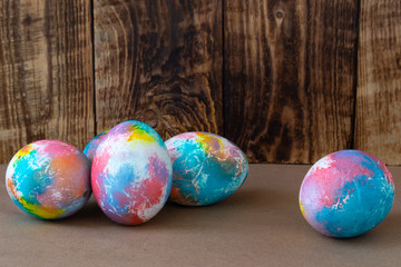 Colorful Easter eggs on a kraft paper against wooden background, space for text
