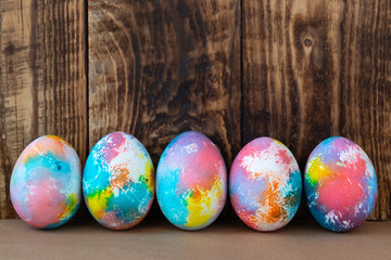 Colorful Easter eggs on a kraft paper against wooden background, space for text