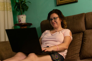 Middle-aged woman using laptop on sofa at home