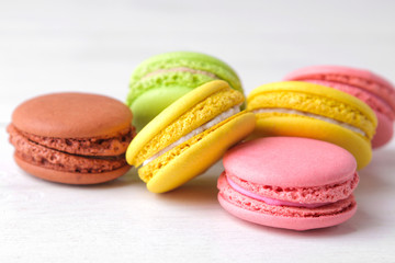 macaroons. delicious colored french macaroni cakes on a white wooden table.