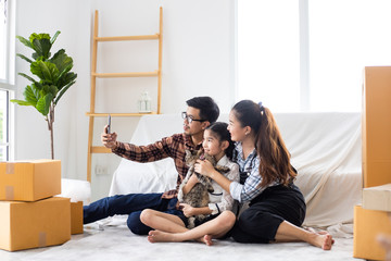 Asian couple husband and wife just moveing to new house and selfie together with smartphone happy and smile face in white living room