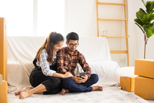 Asian couple husband and wife just moveing to new house and selfie together with smartphone happy and smile face in white living room