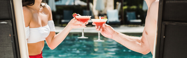 panoramic shot of man and woman clinking cocktail glasses