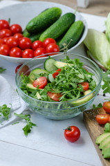 Fresh salad with cucumbers, cherry tomatoes, arugula, avocado, baby corn on white background. Vegetables on wood. Bio Healthy food, herbs and spices. Organic vegetables on wood.