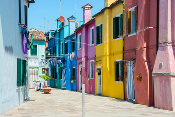 Fototapeta na wymiar A street with colorful houses where laundry is dried on the island of Burano, Italy