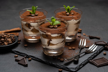 Classic tiramisu dessert in a glass on stone serving board on dark concrete background