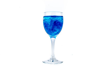 Blue food coloring diffuse in water inside wine glass with empty copyspace area for slogan or advertising text message, over isolated white background.