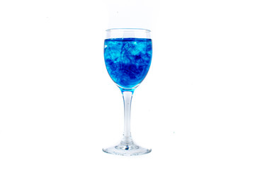 Blue food coloring diffuse in water inside wine glass with empty copyspace area for slogan or advertising text message, over isolated white background.