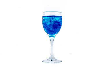 Blue food coloring diffuse in water inside wine glass with empty copyspace area for slogan or advertising text message, over isolated white background.