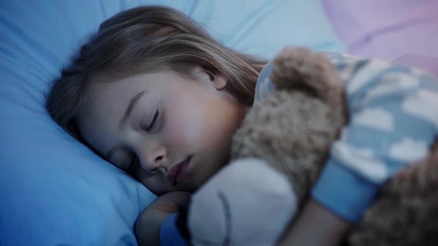 cute kid with teddy bear closing eyes and falling asleep while light turning off