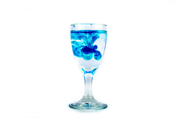 Blue food coloring diffuse in water inside wine glass with empty copyspace area for slogan or advertising text message, over isolated white background.
