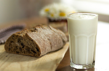 Rustic breakfast  with homemade loaf of rye bread on wooden cutting board and glass of homemade yogurt