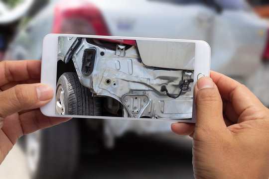 Car insurance agents take pictures of accident-damaged with smartphone for insurance claim.