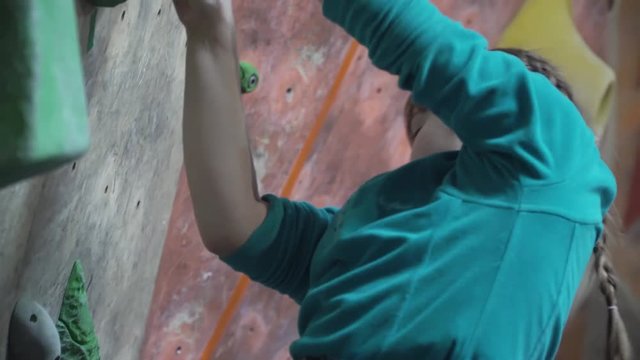 A little girl climbs up against the wall. Children train in a climbing gym. 4K