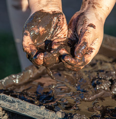 Hands of a boy in black mud on nature
