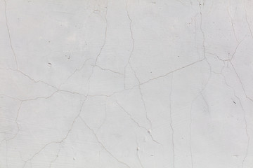 White wall with cracked plaster as abstract background