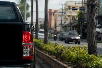 Luxury of black car stop on the asphalt junction by traffic light control in across. Traveling in the provinces during the bright period. Open light brake. With tree and city.