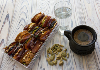 Dates, coffee cup, cardamom and glass of water - Ramadan post, fast food.