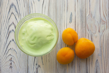 Summer food - pistachio ice cream in glass bowl and apricots on the wooden gray background
