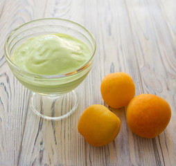 Summer food - pistachio ice cream in glass bowl and apricots on the wooden gray background