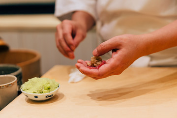 Japanese Omakase Chef making Chutoro Sushi (Medium Fatty Bluefin Tuna), pasting fresh wasabi neatly by hands. Japanese traditional and luxury meal.