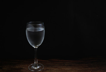 Glass of cold drink water on wooden desk and black background.Clear mineral water,good for health