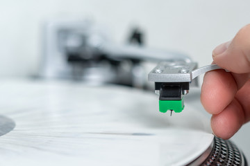 Turntable vinyl record player. White limited vinyl record. Closeup putting tonearm on the turntable