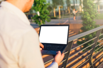 Close up of businessman using blank screen laptop outdoors.