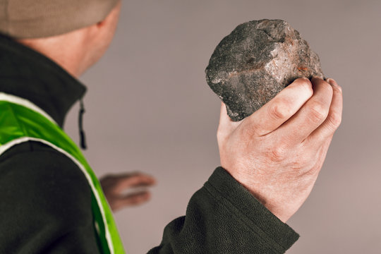 Rebel or protesting worker in a yellow vest with a brick in his hands on a gray background