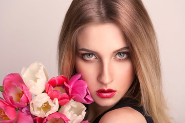 Obraz na płótnie Canvas blonde face, gray eyes, tulips flowers