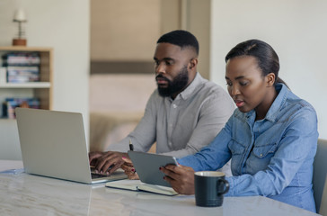 Young African American couple doing online banking together at home