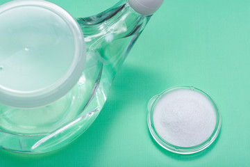 Neti Pot with Soft Comfort Tip and pile of saline (sodium bicarbonate and sodium chloride) on green background. Sinus wash. Nasal irrigation.
