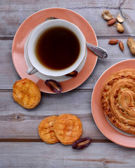 Cup of tea. Sweet bun. Peanuts. Dried peaches and plums. Wood background. Dried fruits. Top view. Rustic. Still life.