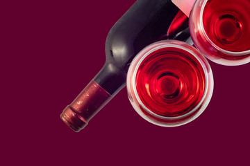  Two glasses with red wine and a bottle of wine on a dark red background