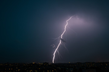 Naklejka na ściany i meble Bright lightning at night over the city during a thunderstorm