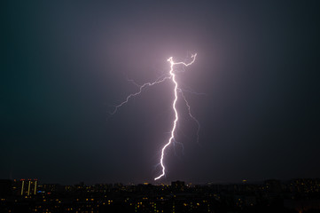 Bright lightning at night over the city during a thunderstorm