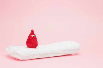 Medical conception photo. Red dreamy smile crochet blood drop, daily or menstrual pad. Woman critical days, gynecological menstruation cycle. Menstruation sanitary feminine hygiene.