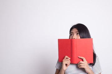 Young Asian woman with a book cover her face.