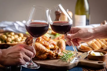 Rolgordijnen toasting with wine glasses in front of chicken dinner © ahirao