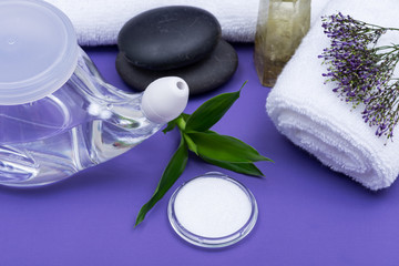 Obraz na płótnie Canvas Spa purple background with Neti Pot, pile of Saline, rolled up White Towels, stacked Basalt Stones and Bamboo Leaves. Sinus wash. Nasal irrigation.