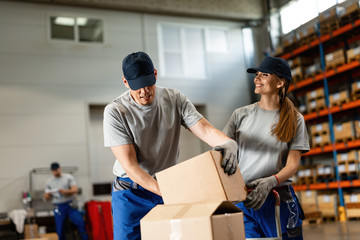 Two workers preparing packages for shipment in a warehouse.