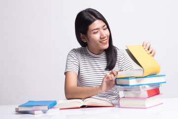 Young Asian woman read a book with books on table.