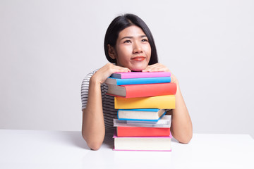 Happy young Asian woman read a book with books on table.