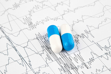 Close-up photo of white and blue pills on EKG graph