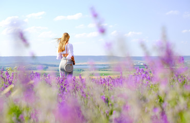 Girl with handbag in skirt and white blouse on lavender field in summer