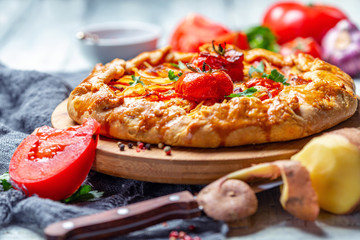 Open pie with potatoes, bacon, onions and tomatoes.