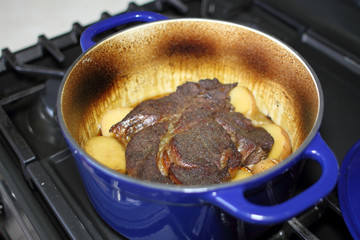 Beef pot roast in a Dutch oven baked with onions and potatoes.