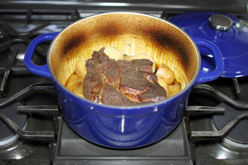 Beef pot roast in a Dutch oven baked with onions and potatoes.