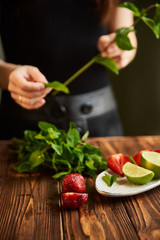 lime strawberry mint ingredients for making lemonade on white plate on wooden table