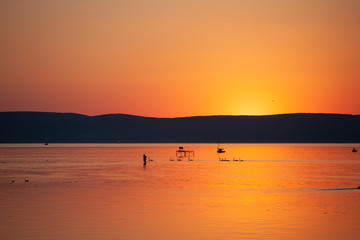 Beautiful sunset in orange color over lake Balaton with silhouettes in Hungary